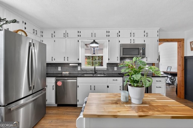 1724 Cedar Grove Church Rd, Winder, GA 30680 - kitchen featuring stainless steel appliances, a textured ceiling, wood finished floors, white cabinets, and tasteful backsplash