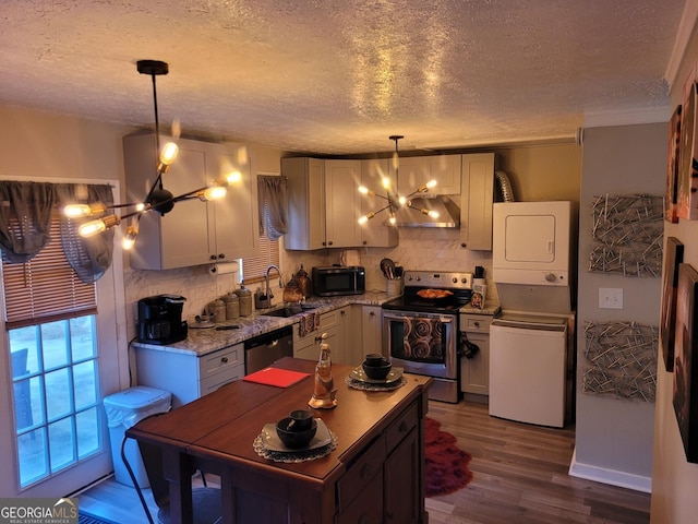 1625 Conley Rd Unit 229, Conley, GA 30288 - kitchen featuring stainless steel appliances, a chandelier, wall chimney range hood, stacked washer and clothes dryer, and a textured ceiling