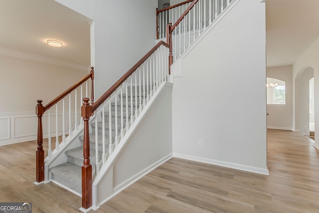 70 Trinity Ln, Covington, GA 30016 - staircase featuring arched walkways, wood finished floors, a chandelier, and ornamental molding
