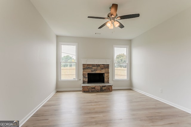 70 Trinity Ln, Covington, GA 30016 - unfurnished living room featuring a stone fireplace, a ceiling fan, and light wood-type flooring