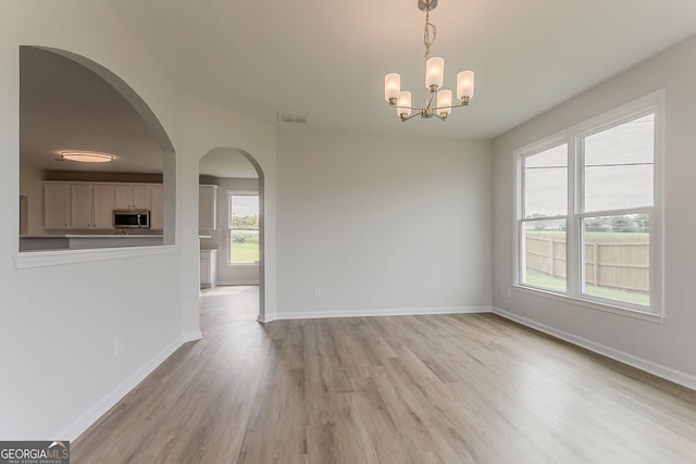 70 Trinity Ln, Covington, GA 30016 - empty room featuring light wood-style flooring, a chandelier, and arched walkways