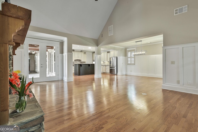 43 Beacon Crst, Newnan, GA 30265 - unfurnished living room with a decorative wall, high vaulted ceiling, light wood-style flooring, a chandelier, and wainscoting