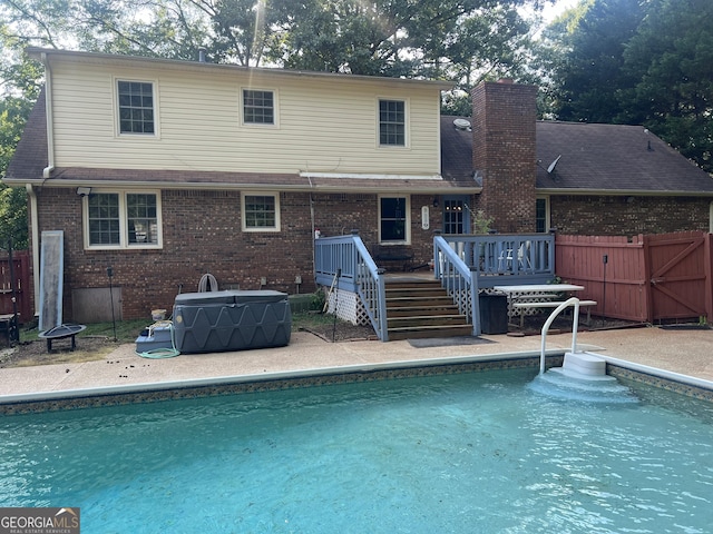 2203 Honeybee Creek Dr, Griffin, GA 30224 - back of house featuring a deck, an outdoor pool, brick siding, and a chimney