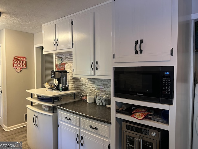 2203 Honeybee Creek Dr, Griffin, GA 30224 - kitchen with backsplash, dark countertops, dark wood-type flooring, white cabinetry, and a textured ceiling