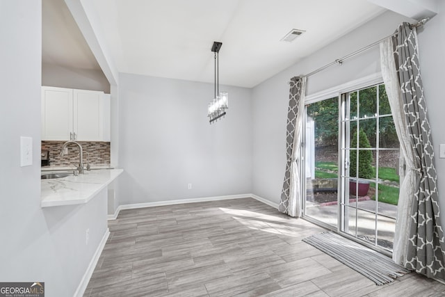 545 Windstone Trl, Alpharetta, GA 30004 - unfurnished dining area with light wood finished floors and a chandelier