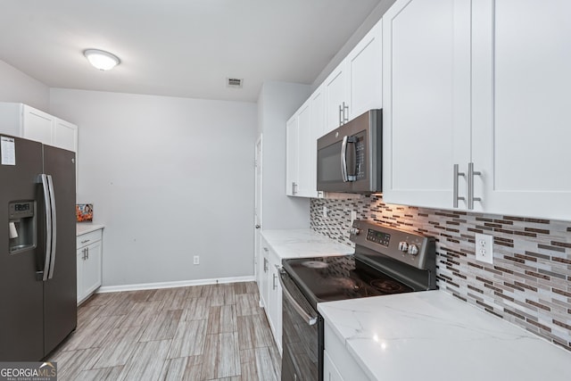 545 Windstone Trl, Alpharetta, GA 30004 - kitchen featuring stainless steel appliances, tasteful backsplash, light stone countertops, white cabinets, and light wood finished floors