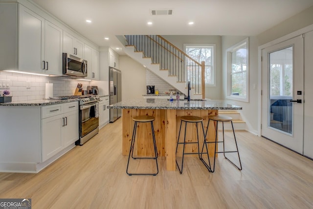 480 Mitchell Rd, Covington, GA 30014 - kitchen featuring stainless steel appliances, light wood finished floors, a kitchen breakfast bar, stone counters, and recessed lighting