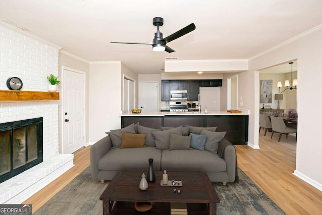 107 Runaway Point Rd, Savannah, GA 31404 - living room featuring light wood-style flooring, ceiling fan, crown molding, a fireplace, and a chandelier