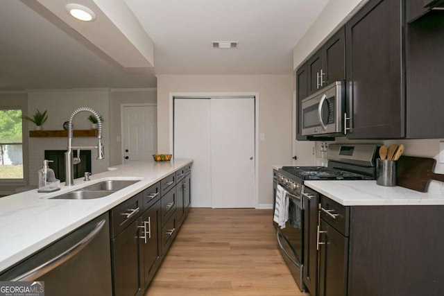 107 Runaway Point Rd, Savannah, GA 31404 - kitchen featuring appliances with stainless steel finishes, light wood-type flooring, dark brown cabinetry, light stone counters, and a peninsula