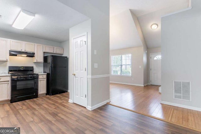 6207 Idlewood Cir, Lithonia, GA 30038 - kitchen with black appliances, under cabinet range hood, light wood-style floors, light countertops, and lofted ceiling