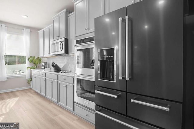 1049 Bodega Loop, Locust Grove, GA 30248 - kitchen featuring stainless steel appliances, light wood-style floors, decorative backsplash, and light countertops