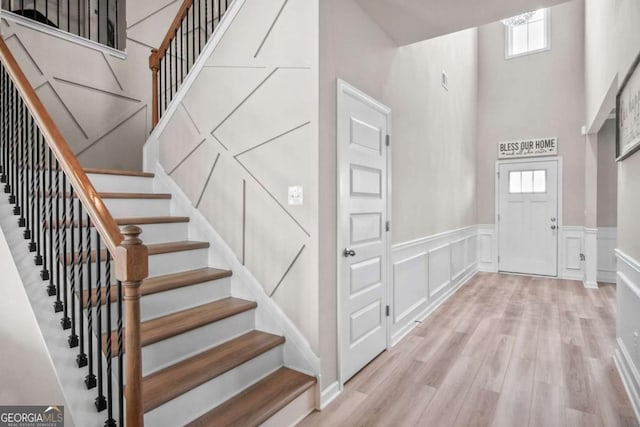 1049 Bodega Loop, Locust Grove, GA 30248 - foyer featuring healthy amount of natural light, a high ceiling, stairway, wood finished floors, and wainscoting