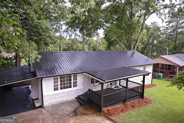 235 Cindy St, Jackson, GA 30233 - back of house with brick siding, a lawn, a metal roof, and view of wooded area