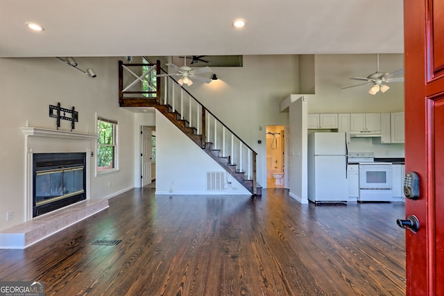 967 Saddle Gap Dr, Clayton, GA 30525 - unfurnished living room featuring ceiling fan, a towering ceiling, stairway, dark wood-style flooring, and a glass covered fireplace