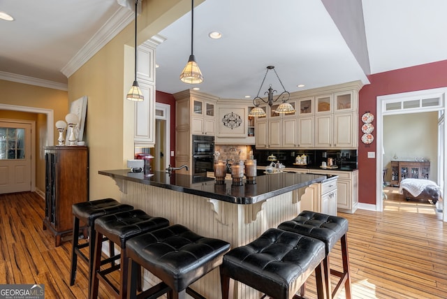 1770 Whippoorwill Rd, Watkinsville, GA 30677 - kitchen with cream cabinetry, backsplash, a kitchen breakfast bar, light wood finished floors, and ornamental molding