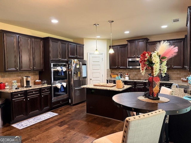 173 Lavender Way, Mcdonough, GA 30252 - kitchen featuring appliances with stainless steel finishes, dark brown cabinets, dark wood-style floors, decorative backsplash, and decorative light fixtures