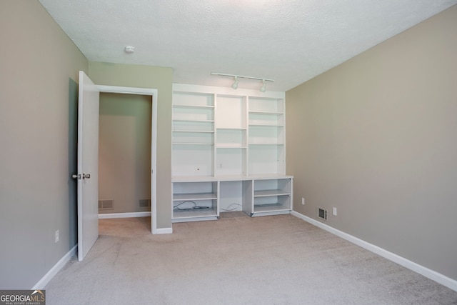 717 Raven Springs Trl, Stone Mountain, GA 30087 - unfurnished bedroom featuring light colored carpet, a textured ceiling, and track lighting
