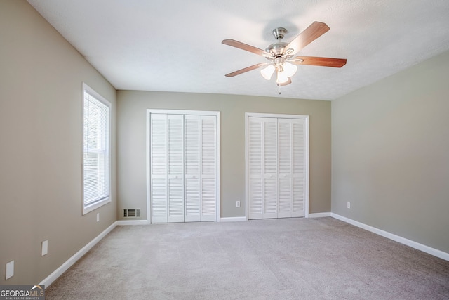717 Raven Springs Trl, Stone Mountain, GA 30087 - unfurnished bedroom featuring two closets, multiple windows, and light carpet