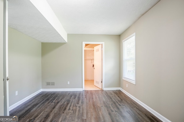 717 Raven Springs Trl, Stone Mountain, GA 30087 - unfurnished bedroom featuring dark wood-type flooring, a textured ceiling, and a walk in closet