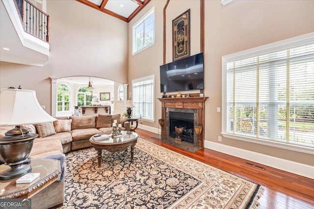 311 N Rivoli Farms Dr, Macon, GA 31210 - living room featuring a towering ceiling, hardwood / wood-style floors, a fireplace, arched walkways, and crown molding