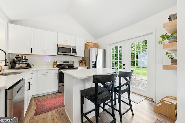 4829 Caboose Ln NW, Acworth, GA 30102 - kitchen with stainless steel appliances, light wood-style floors, a kitchen breakfast bar, light countertops, and high vaulted ceiling