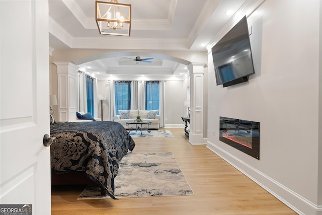 896 Bobby Jones Dr, Dublin, GA 31021 - bedroom with ornate columns, a tray ceiling, arched walkways, light wood-type flooring, and ornamental molding