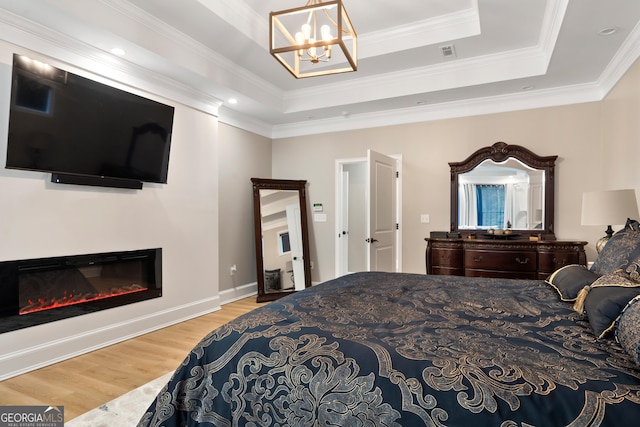 896 Bobby Jones Dr, Dublin, GA 31021 - bedroom with wood finished floors, a raised ceiling, a chandelier, a glass covered fireplace, and crown molding
