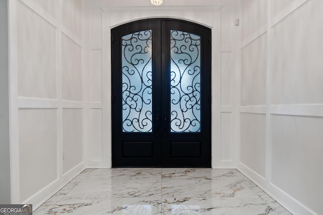 896 Bobby Jones Dr, Dublin, GA 31021 - foyer entrance with french doors, marble look tiles, arched walkways, and a decorative wall
