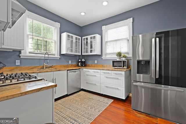 303 W 39th St, Savannah, GA 31405 - kitchen with appliances with stainless steel finishes, white cabinetry, butcher block countertops, glass insert cabinets, and dark wood finished floors