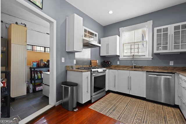 303 W 39th St, Savannah, GA 31405 - kitchen with stainless steel appliances, under cabinet range hood, white cabinets, glass insert cabinets, and healthy amount of natural light