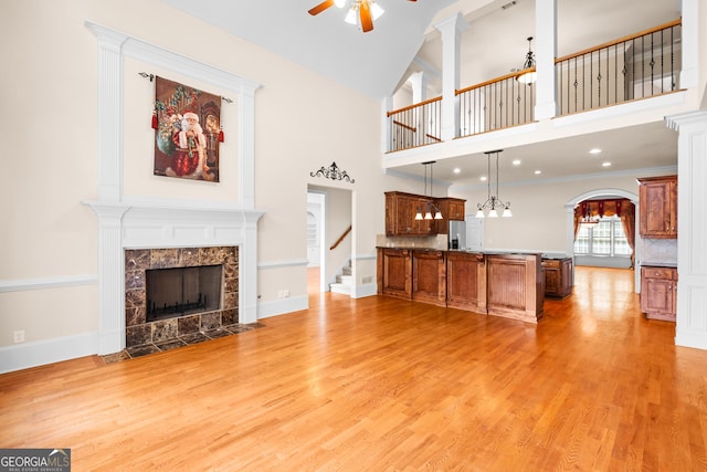 1005 Lyndhurst Way SE, Conyers, GA 30013 - unfurnished living room with a ceiling fan, a fireplace, light wood-style floors, arched walkways, and stairs