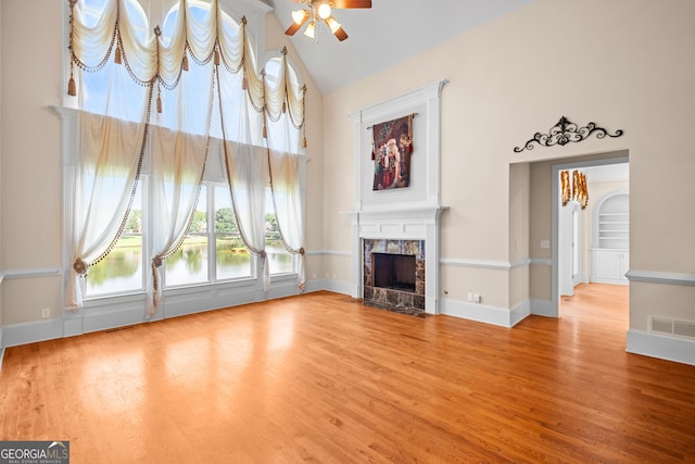 1005 Lyndhurst Way SE, Conyers, GA 30013 - unfurnished living room with ceiling fan, a tiled fireplace, high vaulted ceiling, and wood finished floors