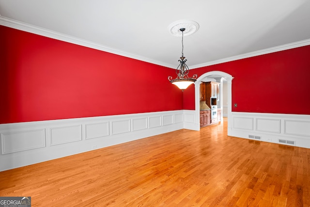 1005 Lyndhurst Way SE, Conyers, GA 30013 - unfurnished room featuring arched walkways, crown molding, wainscoting, wood finished floors, and decorative columns