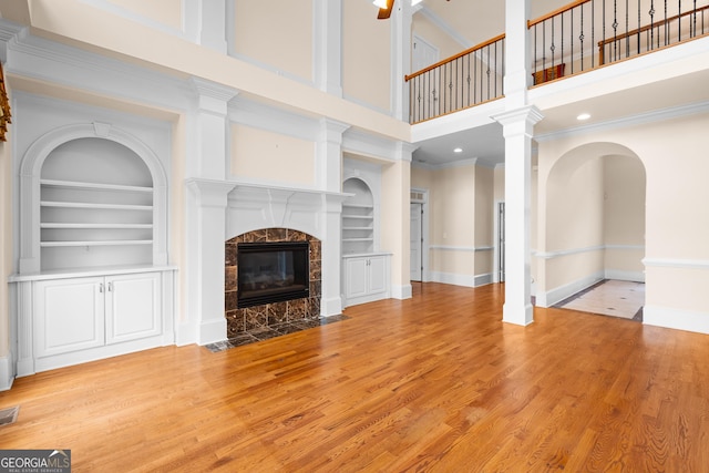 1005 Lyndhurst Way SE, Conyers, GA 30013 - unfurnished living room featuring a fireplace, light wood-style floors, a high ceiling, built in features, and ornamental molding