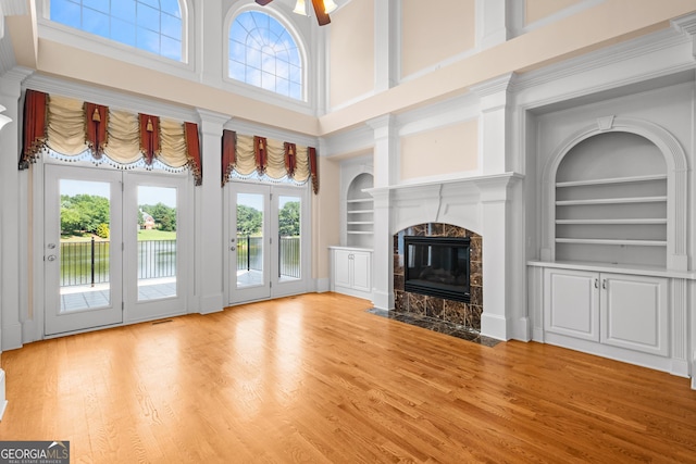 1005 Lyndhurst Way SE, Conyers, GA 30013 - unfurnished living room featuring built in shelves, a fireplace, wood finished floors, and a high ceiling
