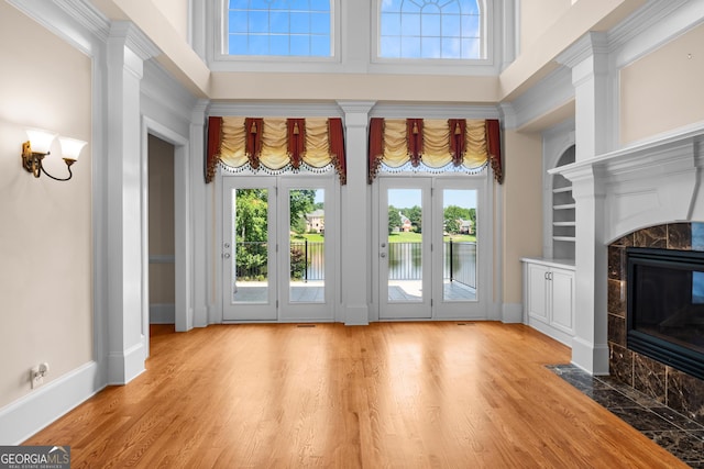 1005 Lyndhurst Way SE, Conyers, GA 30013 - unfurnished living room with a high end fireplace, light wood-style flooring, built in features, a water view, and a towering ceiling