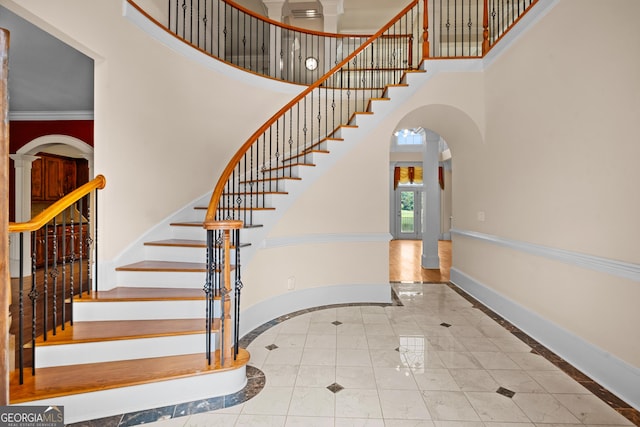 1005 Lyndhurst Way SE, Conyers, GA 30013 - staircase featuring a towering ceiling, inlaid floor details, arched walkways, ornamental molding, and tile patterned flooring