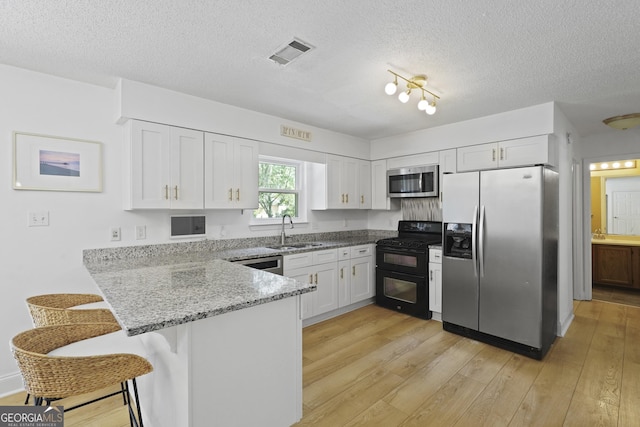 126 S Sheftall Cir, Savannah, GA 31410 - kitchen with appliances with stainless steel finishes, a peninsula, light stone counters, white cabinetry, and a textured ceiling