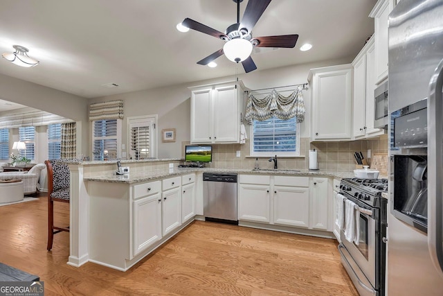 236 Creek View Ln, Acworth, GA 30102 - kitchen featuring appliances with stainless steel finishes, a peninsula, a ceiling fan, white cabinetry, and a kitchen bar