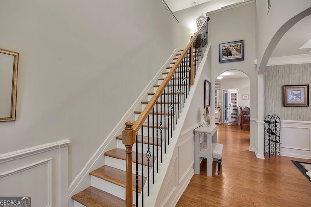 236 Creek View Ln, Acworth, GA 30102 - stairway featuring arched walkways, a decorative wall, wood finished floors, a high ceiling, and wainscoting