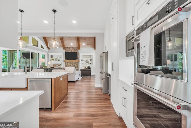 123 River Point Rd, Jackson, GA 30233 - kitchen with appliances with stainless steel finishes, light wood-style floors, hanging light fixtures, white cabinetry, and ornamental molding
