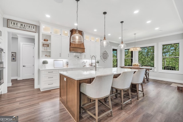 123 River Point Rd, Jackson, GA 30233 - kitchen featuring light countertops, a kitchen island with sink, white cabinets, glass insert cabinets, and crown molding