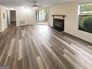 6353 Wedgeview Ct, Tucker, GA 30084 - unfurnished living room featuring a glass covered fireplace, wood finished floors, and ceiling fan