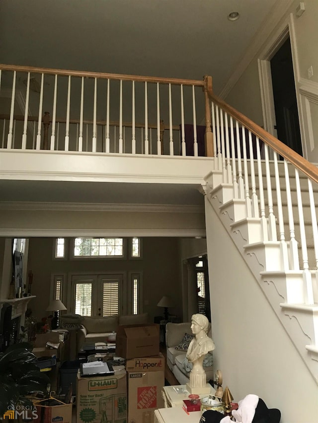 stairway featuring crown molding, a towering ceiling, and french doors