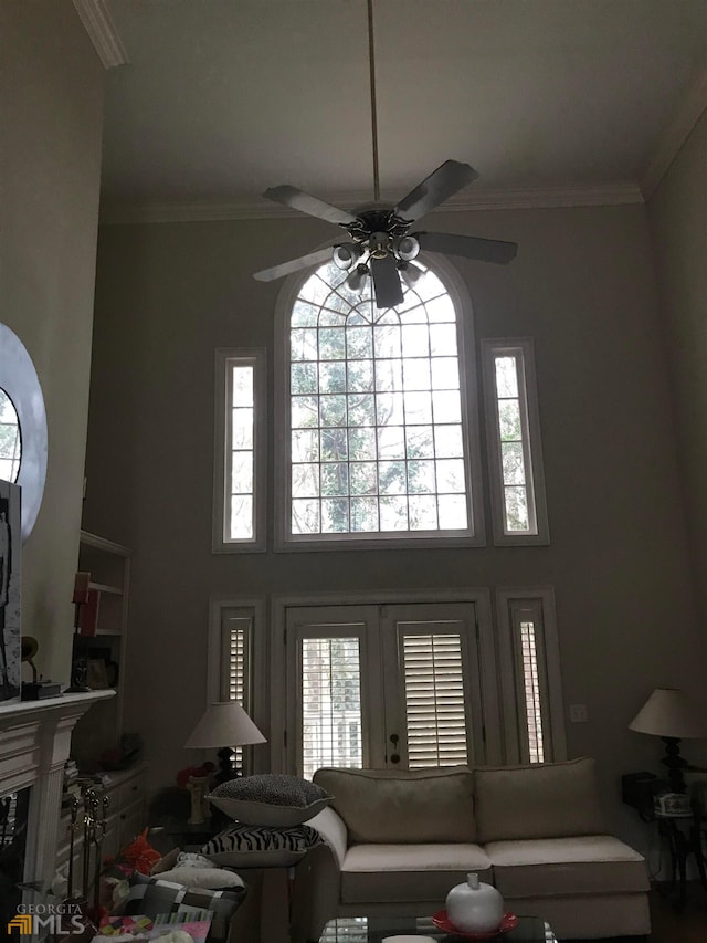 living room featuring french doors, ceiling fan, crown molding, a fireplace, and a high ceiling