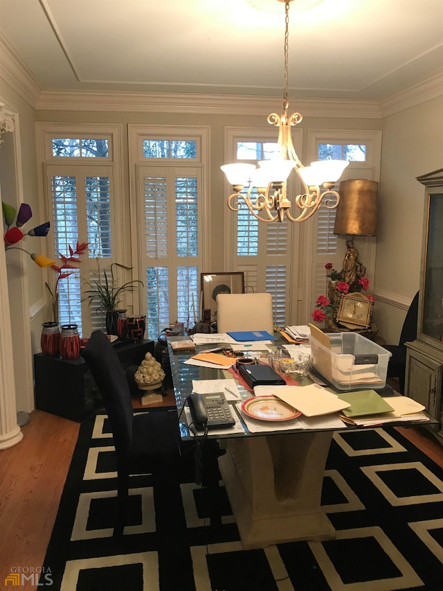 dining area featuring crown molding, wood-type flooring, a healthy amount of sunlight, and a notable chandelier