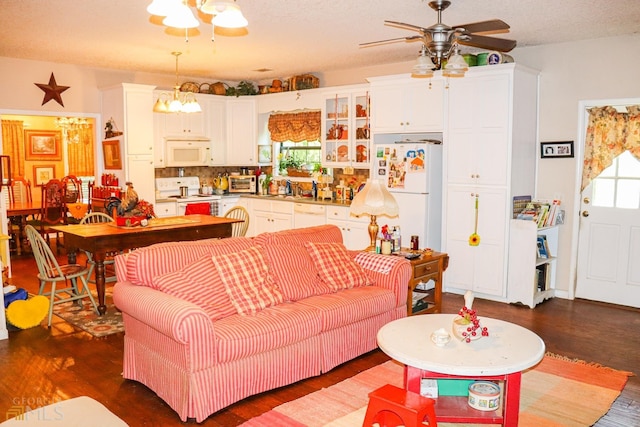 living room featuring dark hardwood / wood-style flooring, ceiling fan with notable chandelier, and sink