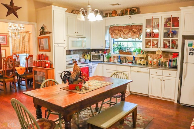 kitchen featuring dark hardwood / wood-style flooring, an inviting chandelier, tasteful backsplash, white appliances, and hanging light fixtures