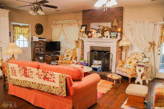 living room with brick wall, a brick fireplace, dark hardwood / wood-style flooring, and ceiling fan