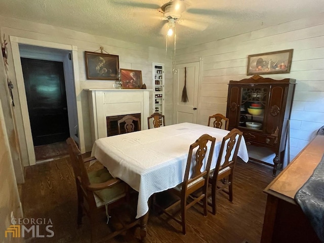 dining space with ceiling fan, dark wood-type flooring, and a textured ceiling